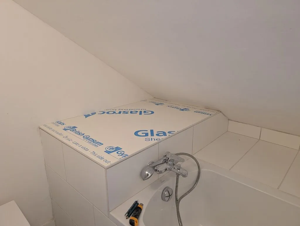 Test-fitting a piece of water-resistant drywall to cover the utility area (there are two columns near the far corner to support the board at all edges).