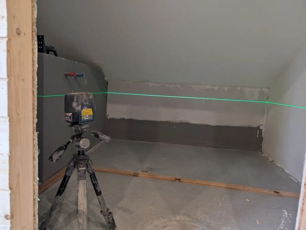 Using a laser level to mark the final height of the bathtub walls.
