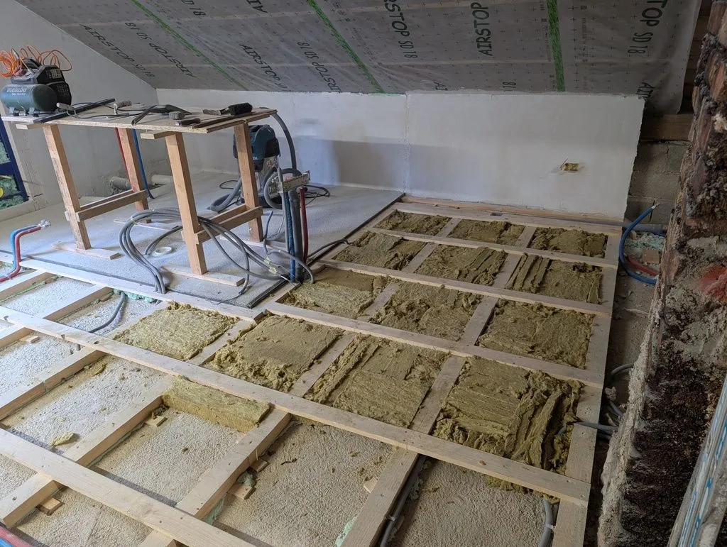 The first pieces of glass wool packed into the subfloor substructure.
