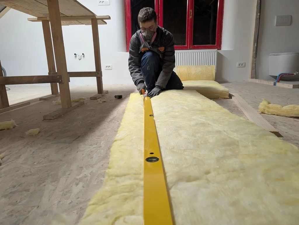 Using a straightedge to cut the glass wool to width.