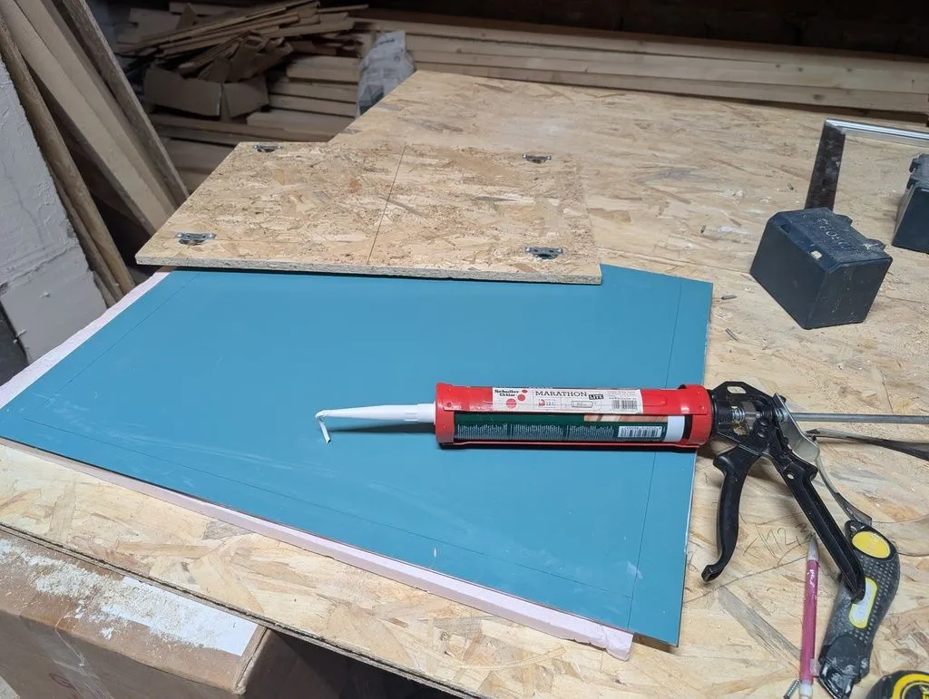 Attaching the mirror to the OSB mounting board with construction adhesive.