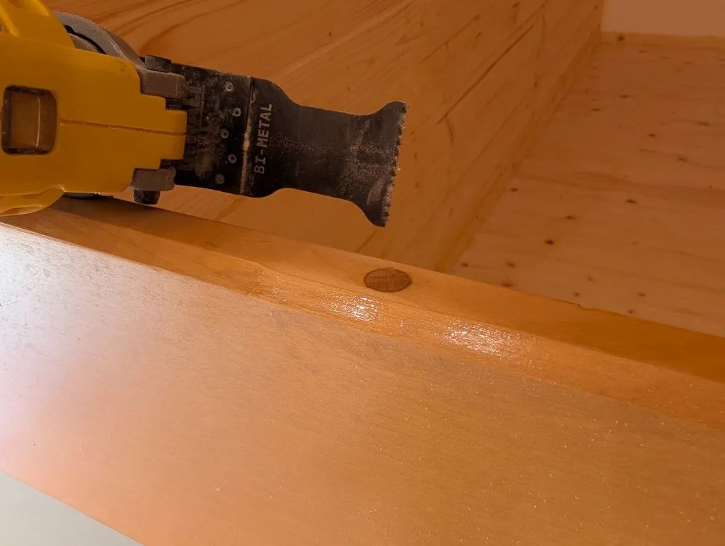 Cutting the dowel flush with the surface of the door. A flexible fine-toothed Japanese hand saw is the correct tool for the job, but I did not have one on hand, and made due with an oscillating multitool.