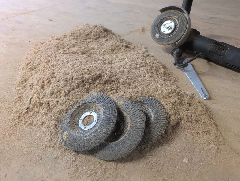 We addressed this relatively heavy-duty job using an angle grinder and flap disks, which are far more aggressive than a orbital sander. You can see all the flap disks we burned through on the job.