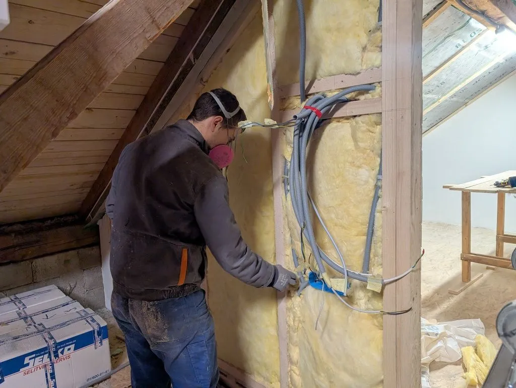 Installing insulation around the conduit near the future electrical panel.