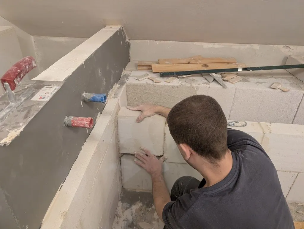 Setting in place the final block of far bathtub wall.