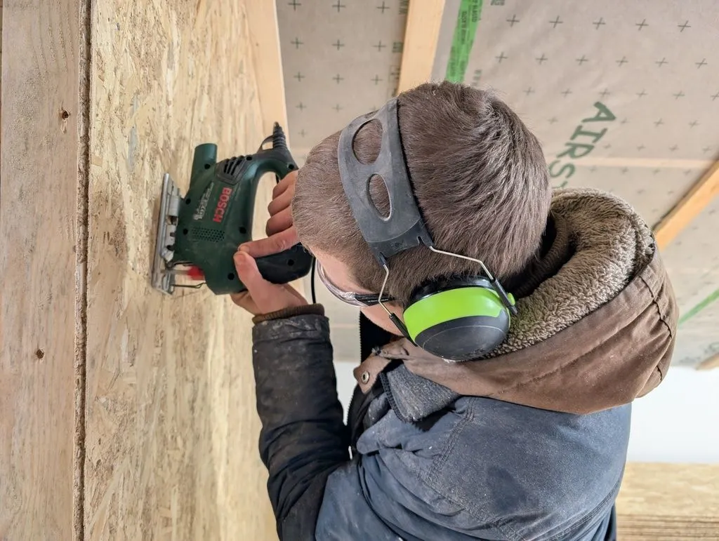 Using a jigsaw to cut a hole for electrical outlets.