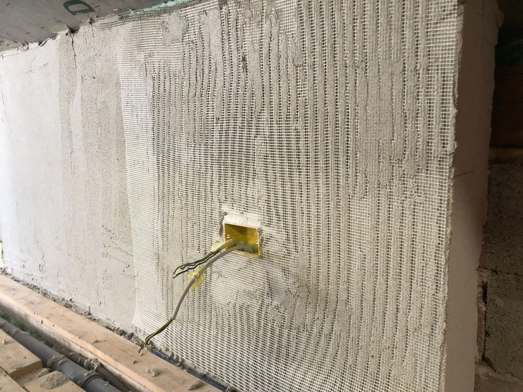 The Multipor blocks are finished similarly to how the process for rendering a masonry wall — first with a base coat of mortar embedded in fiberglass mesh, followed by a trowelled-on finish coat.