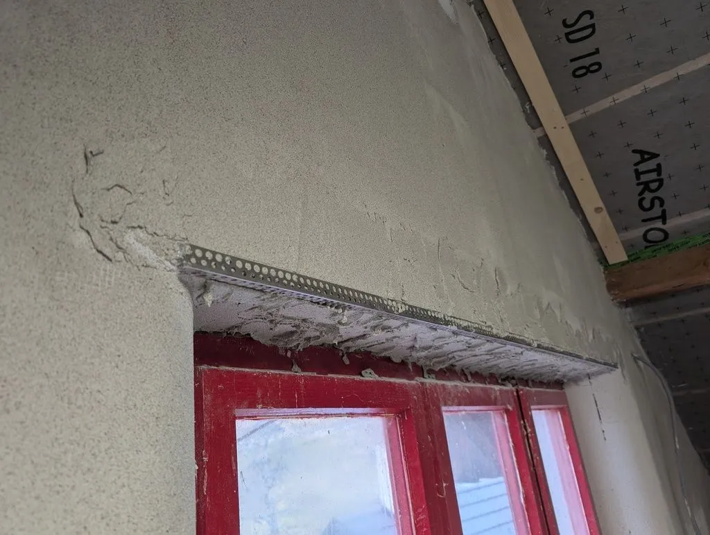 A metal reinforcing bead is placed on along corners, and embedded into the base coat.