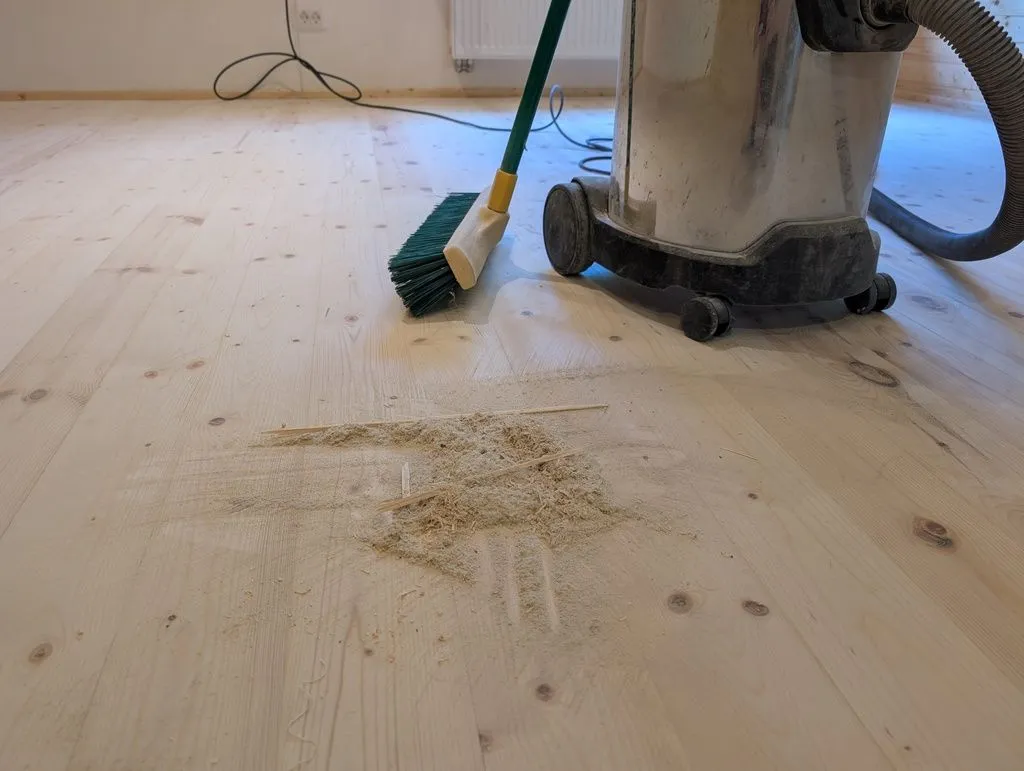 The floor must be thoroughly cleaned between coats: we first swept up sanding dust with a broom and cleaned the floor with a shop vac...