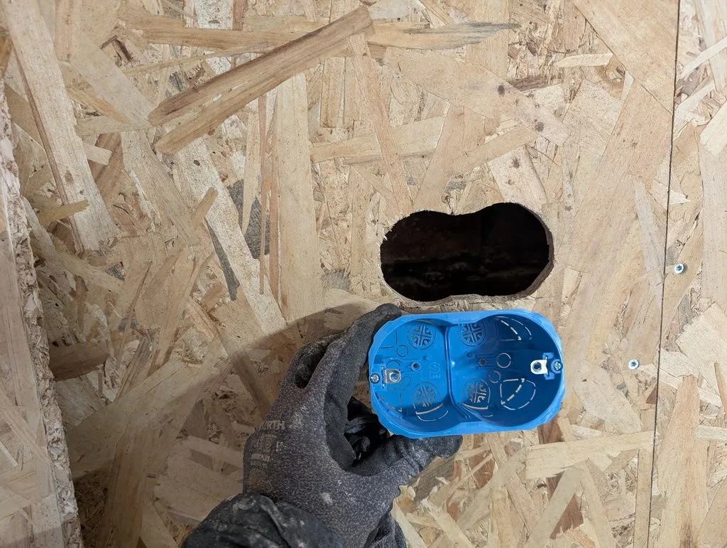 A hole cut in the OSB sheathing for an electrical box that will hold outlets and switches.