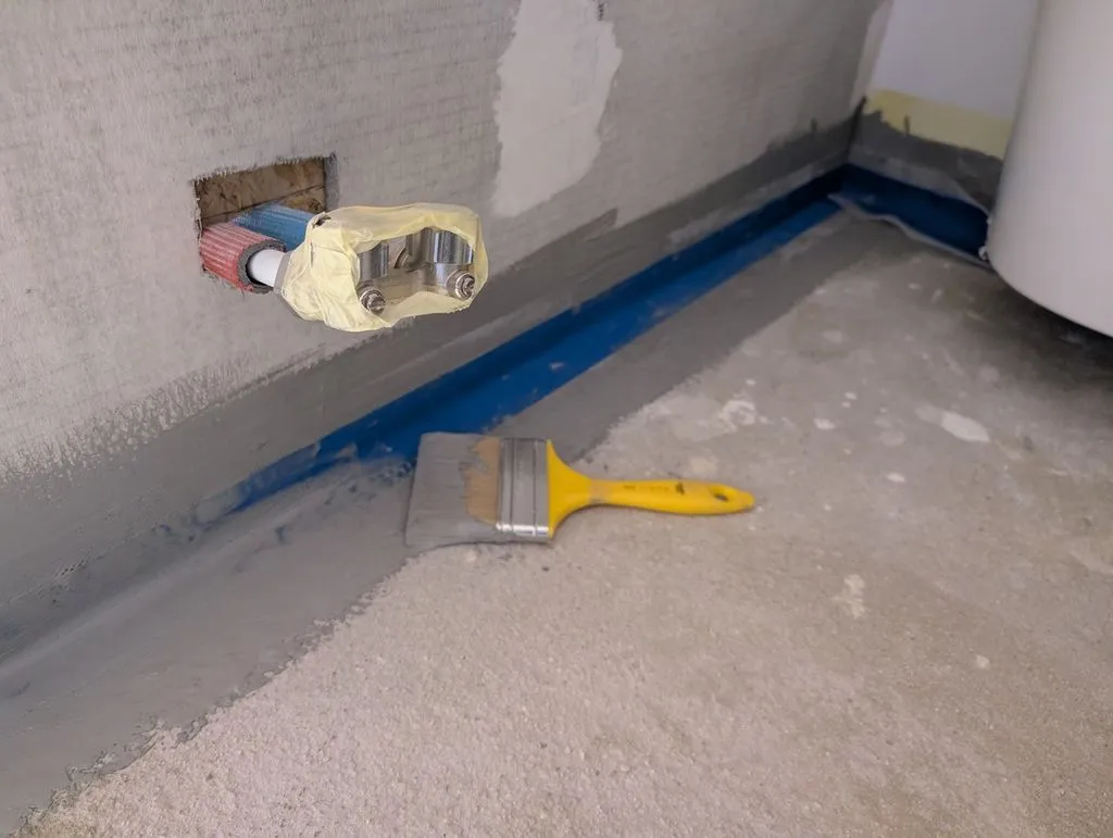 Beginning the waterproofing. The waterproofing compound is applied by brush in two layers. The second layer is applied, with brush strokes perpendicular to the first layer, a few hours after the first layer.