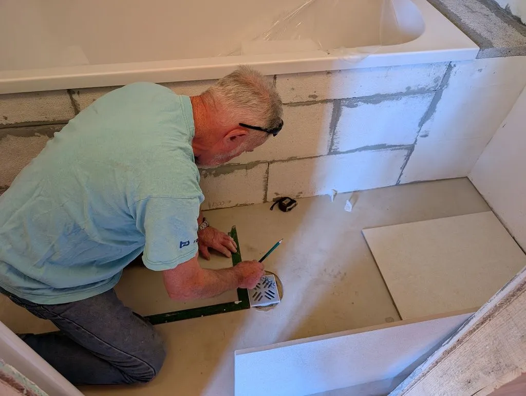 Zdravko taking measurements needed to fit the tiles around the floor drain.