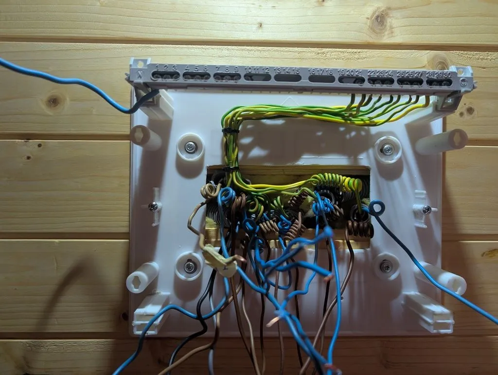 The ground conductors (yellow and green) routed to the ground busbar (top right). I'll then connect the neutrals (blue conductors) to the neutral busbar (top left), and finally install the circuit breakers and wire up the live conductors (brown).