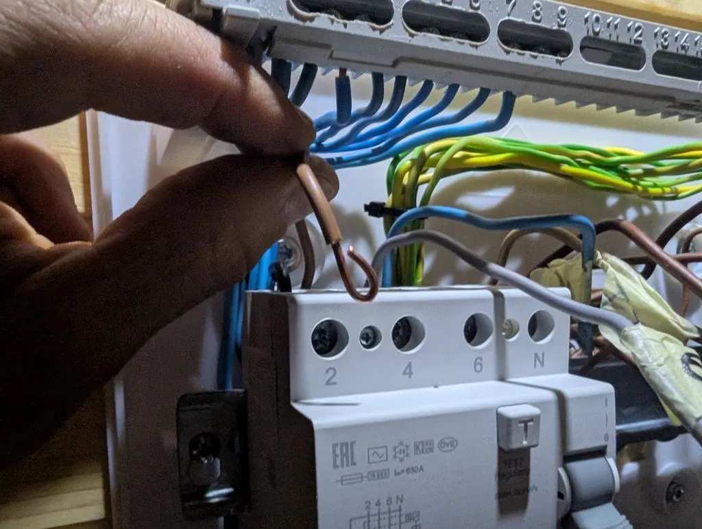 A hook at the end of the conductors (foreground) makes for a better electrical connection in the terminals. The device in the background with the 2/4/6/N terminals is the RCD, which also serves as the main shutoff switch for the attic's electrical supply.