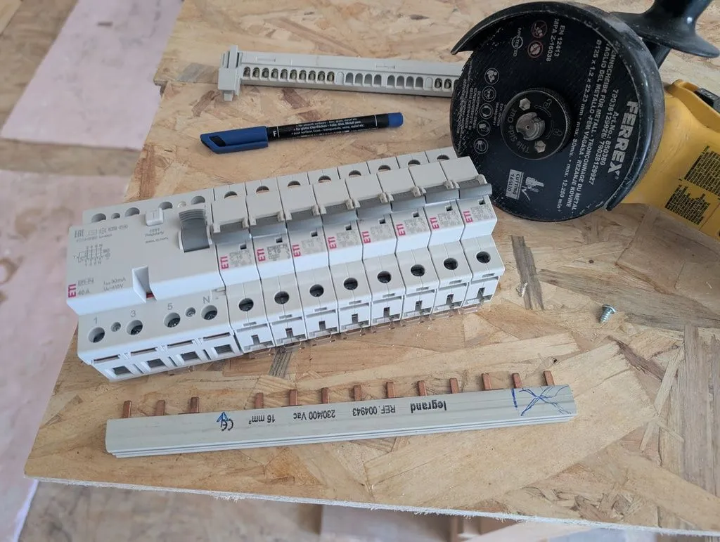 A copper rail (bottom, with projecting copper teeth) connects the supply (from the RCD, the larger device at the left) to the individual miniature circuit breakers (the smaller devices towards the right). Although barely visible from the picture, there are in fact three separate, electrically insulated rails, one for each phase of the three-phase supply. The teeth in the rails connect to terminals in the bottoms of the breakers. The missing tooth at the fourth-from-left position is intentional, so as to avoid the neutral (N) terminal in the RCD.