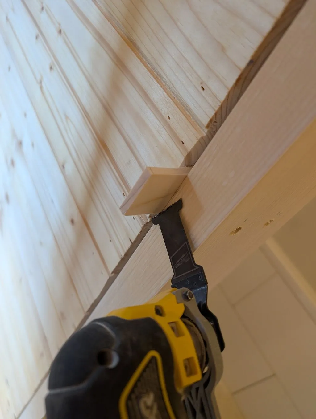 Cutting away the protruding parts of the shims with an oscillating multitool after attaching the jambs.