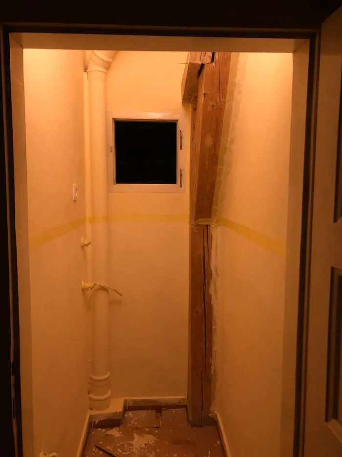 The room after the first coat of paint, with splotches and masking tape visible.