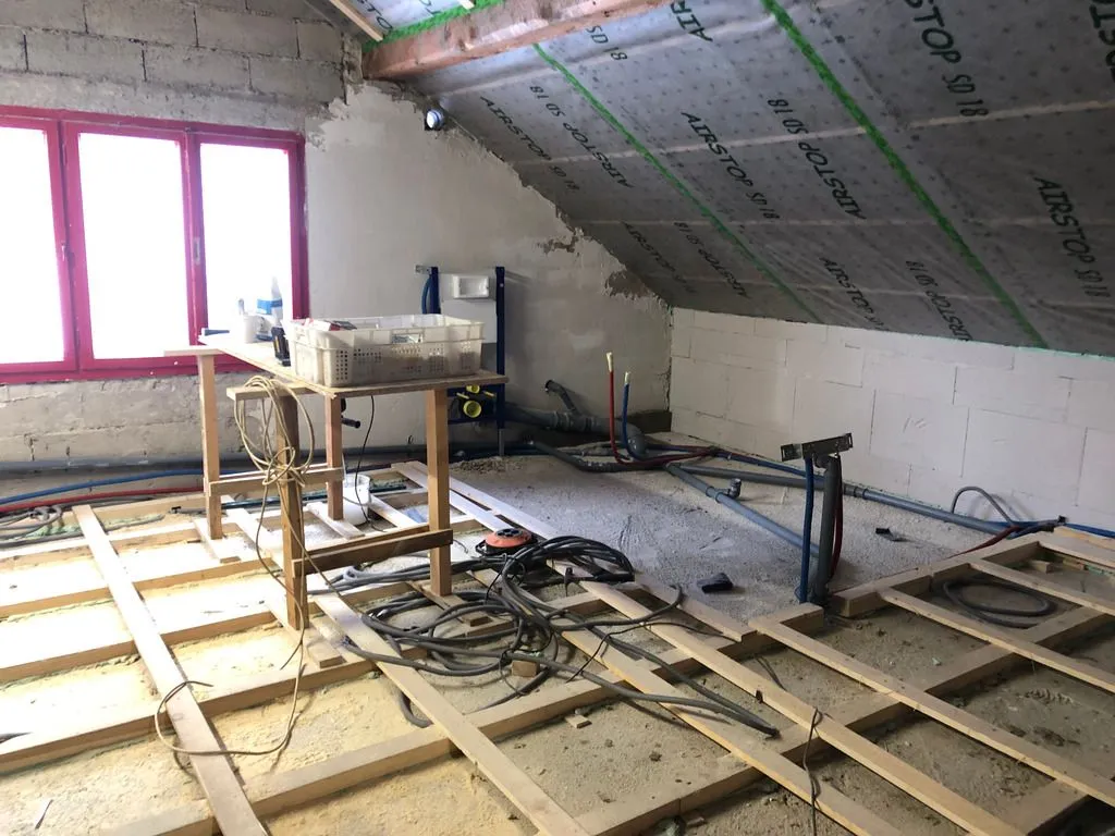 The far corner will hold the bathroom—you can make out the drain lines on the floor for the future bath and sink. (The tubing in the foreground is electrical conduit, unrelated to the plumbing job.)