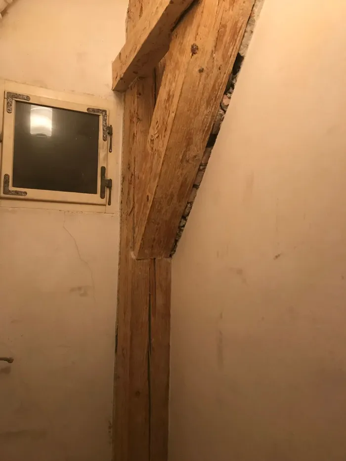 A visible gap running between a brace in the timber framing and the masonry wall.