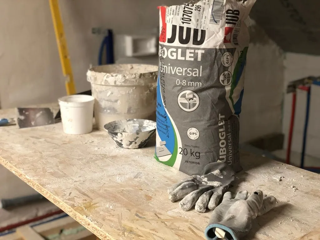 We leveled the wall with a gypsum-based leveling compound, which comes in dry form and is mixed with water to a workable consistency.