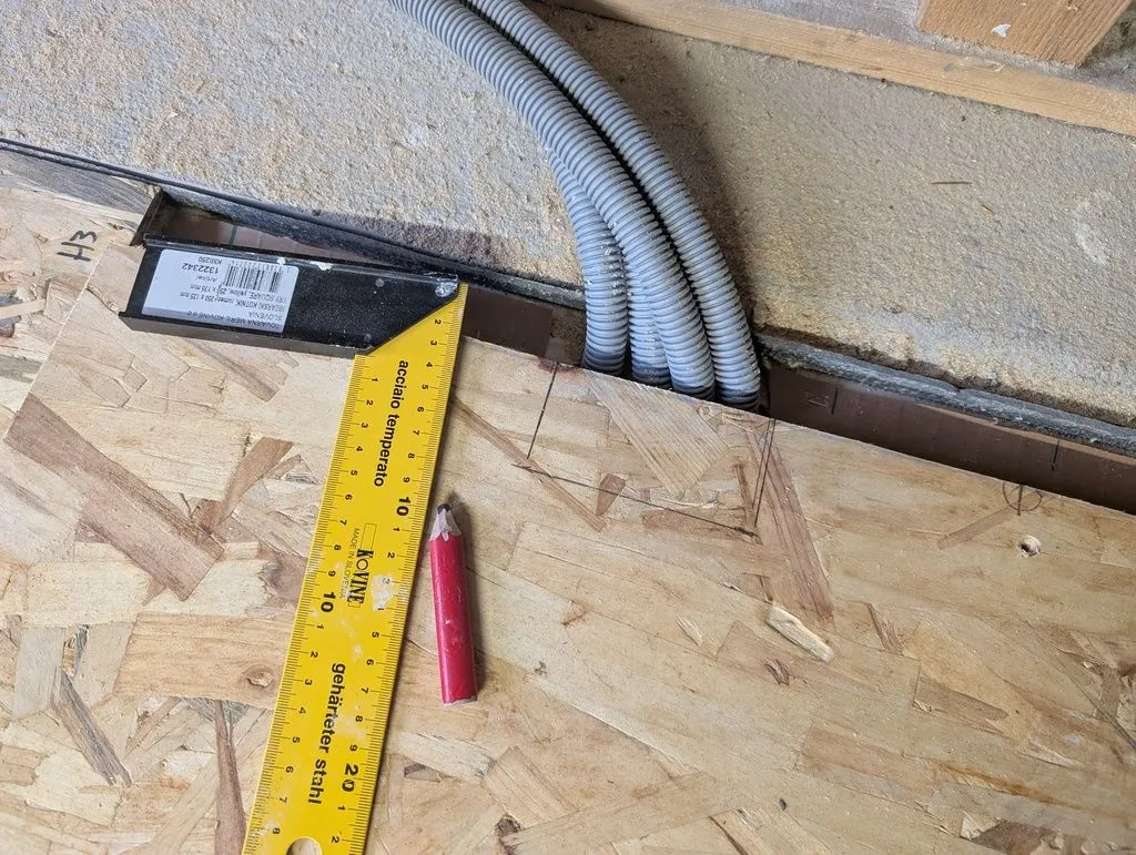 Detail showing the process of notching the subfloor to fit around electrical conduit coming up out of the floor.