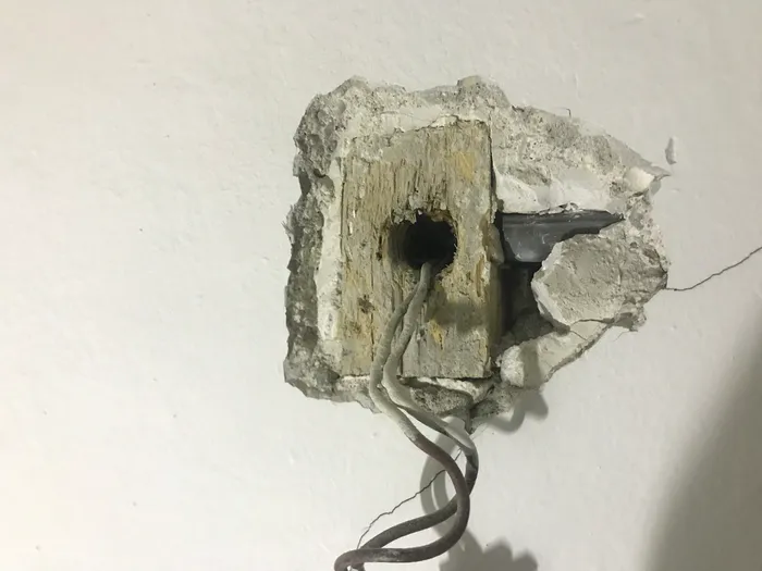 The hewn-out scrap piece of construction lumber originally serving as the room's junction box.