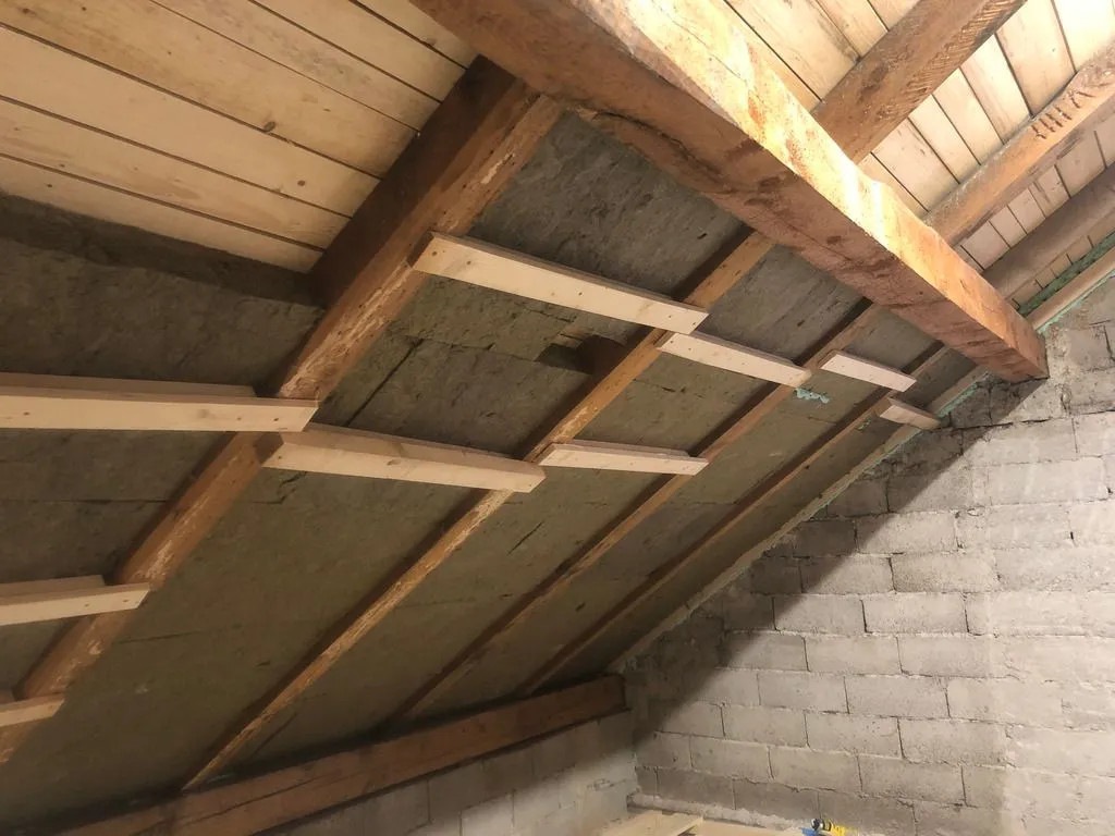 The first layer of rock wool batts (100 mm thick) going in between the rafters. The boards temporarily hold the rock wool batts in place until the polyurethane adhesive on the back cures.