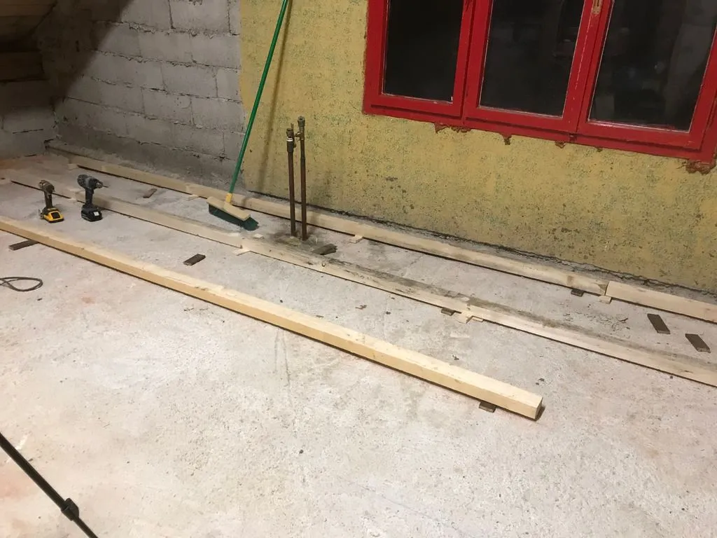 The first sleepers being attached to the concrete floor slab. The sleepers are attached with the Slovene equivalent of TapCon screws ("Turbo vijaki") drilled directly into the concrete, with shims used to level the sleepers. Polyurethane spray foam under the sleepers provides additional support.