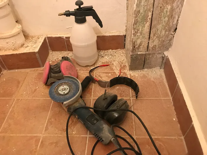 Angle grinder and PPE layed on the floor.